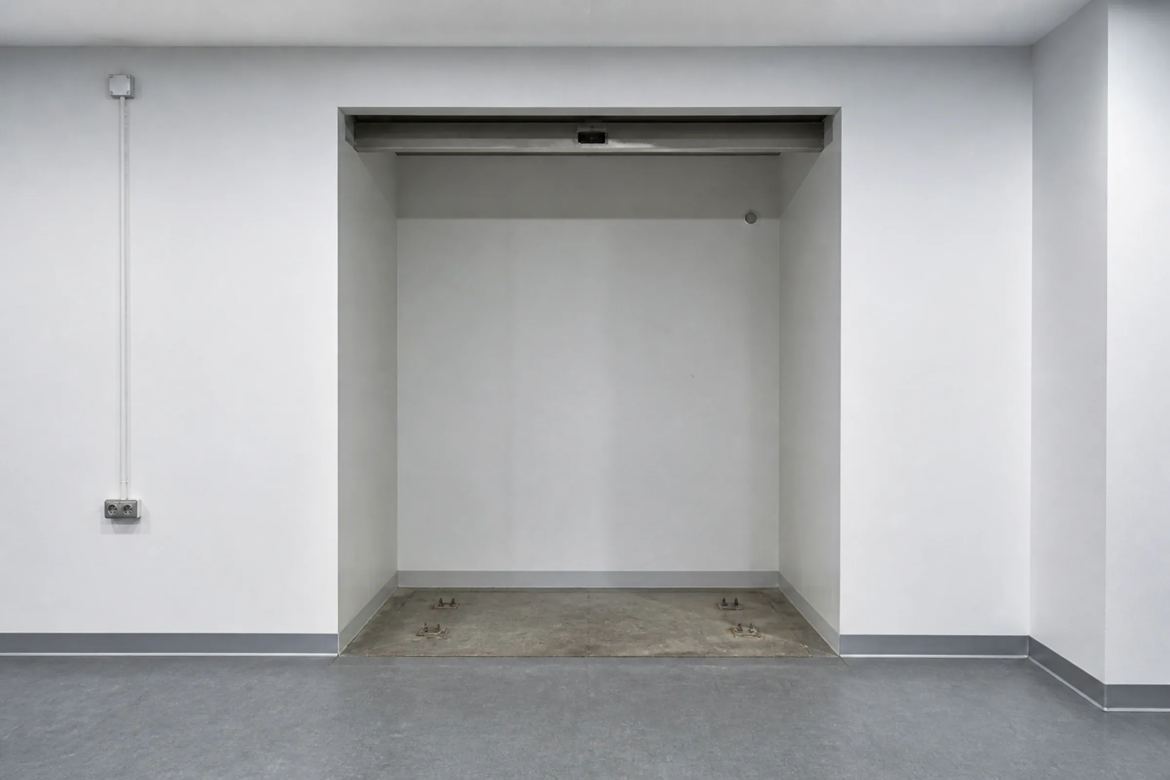 An empty recess in a corridor wall where a vending machine would stand, clean and unoccupied.